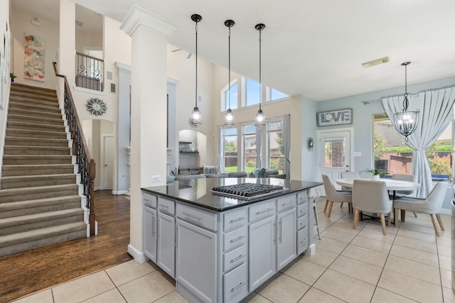 9523 Sapphire Hill Ln, Katy, TX 77494 - kitchen with stainless steel gas cooktop, light tile patterned floors, plenty of natural light, decorative light fixtures, and a towering ceiling