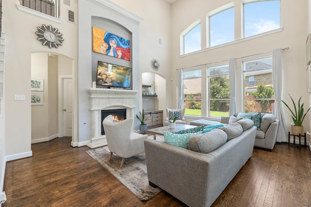 9523 Sapphire Hill Ln, Katy, TX 77494 - living room featuring a high ceiling, a warm lit fireplace, dark wood finished floors, and healthy amount of natural light