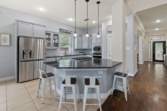 9523 Sapphire Hill Ln, Katy, TX 77494 - kitchen featuring stainless steel appliances, ornamental molding, a kitchen bar, glass insert cabinets, and hanging light fixtures
