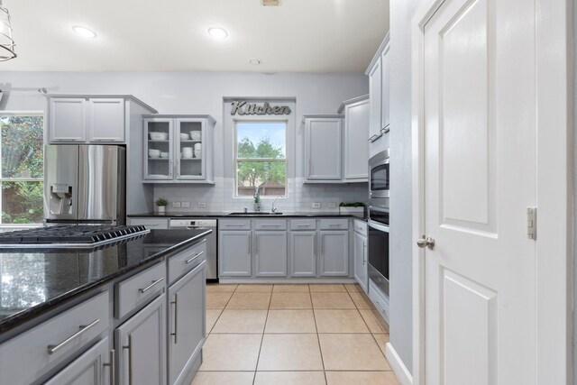 9523 Sapphire Hill Ln, Katy, TX 77494 - kitchen featuring stainless steel appliances, light tile patterned flooring, backsplash, glass insert cabinets, and gray cabinets