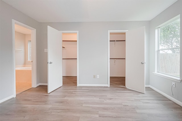 1811 Elm Shadow Dr, Missouri City, TX 77489 - unfurnished bedroom featuring a spacious closet, light wood-style floors, ensuite bathroom, and a closet