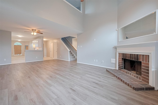 1811 Elm Shadow Dr, Missouri City, TX 77489 - unfurnished living room with light wood finished floors, a ceiling fan, stairs, and a brick fireplace