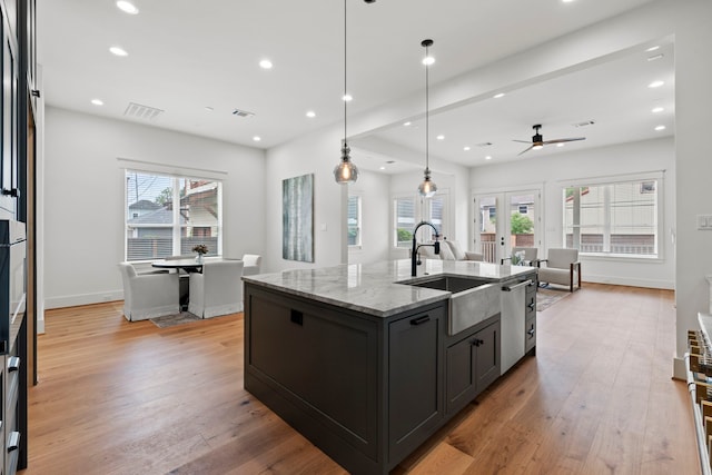 1313 Waverly St, Houston, TX 77008 - kitchen with stainless steel dishwasher, ceiling fan, light stone countertops, light wood-style floors, and french doors