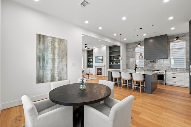 1313 Waverly St, Houston, TX 77008 - dining room with recessed lighting, ceiling fan, light wood-type flooring, and a lit fireplace