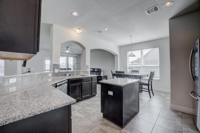 3502 Singing Flower Ln, Richmond, TX 77406 - kitchen with a ceiling fan, appliances with stainless steel finishes, light stone countertops, pendant lighting, and arched walkways