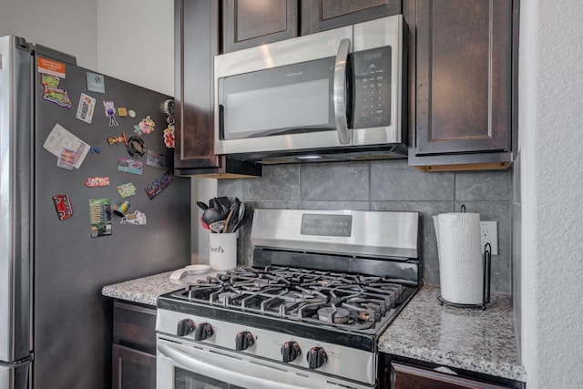 3502 Singing Flower Ln, Richmond, TX 77406 - kitchen with stainless steel appliances, dark brown cabinetry, decorative backsplash, and light stone counters