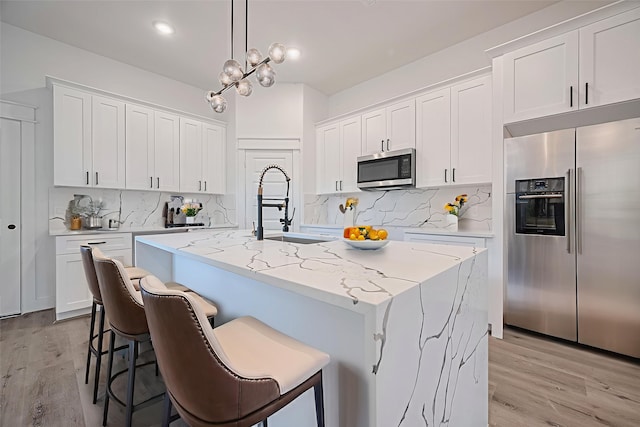 6749 Liverpool St, Houston, TX 77021 - kitchen featuring stainless steel appliances, tasteful backsplash, light wood-type flooring, and white cabinetry
