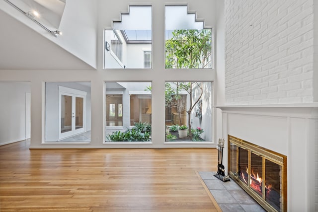 1016 Barkdull St, Houston, TX 77006 - unfurnished living room with light wood-style floors, a brick fireplace, and a high ceiling