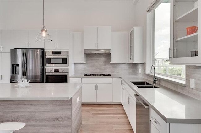 9805 Finch Falls Ln, Houston, TX 77080 - kitchen featuring appliances with stainless steel finishes, under cabinet range hood, light countertops, white cabinets, and hanging light fixtures