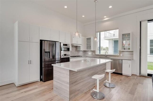 9805 Finch Falls Ln, Houston, TX 77080 - kitchen with appliances with stainless steel finishes, light wood-style flooring, a kitchen breakfast bar, glass insert cabinets, and recessed lighting