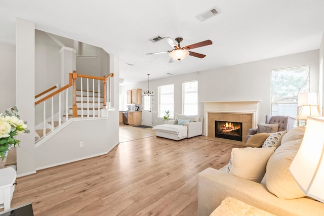 12727 Regal Pine Ln, Houston, TX 77070 - living area featuring light wood finished floors, ceiling fan, a tiled fireplace, and stairs