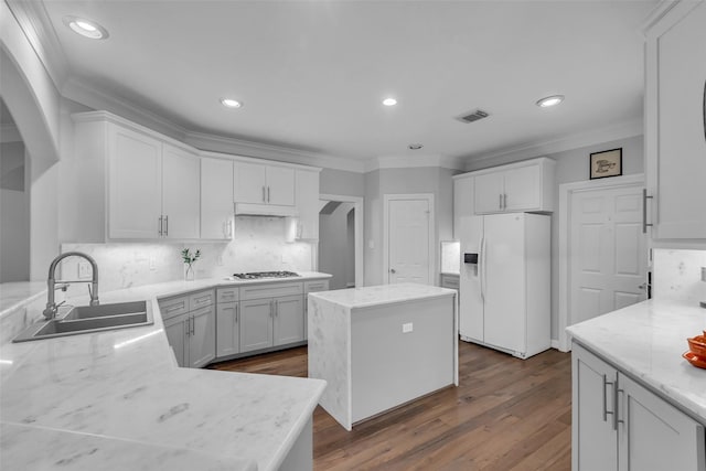 5523 Darschelle Dr, Houston, TX 77069 - kitchen featuring white fridge with ice dispenser, arched walkways, crown molding, tasteful backsplash, and white cabinetry
