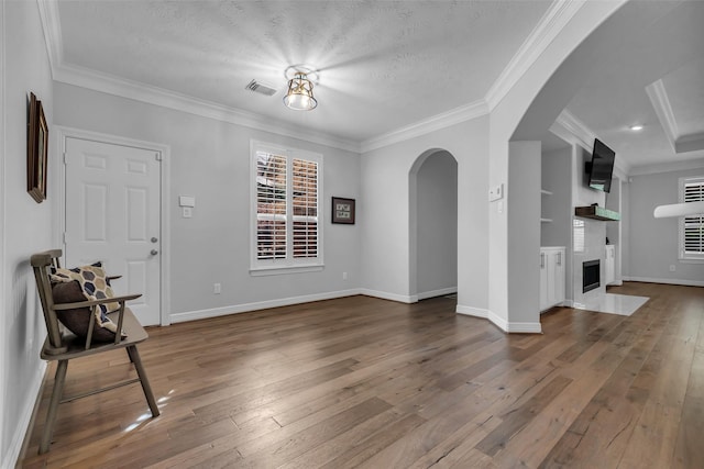 5523 Darschelle Dr, Houston, TX 77069 - unfurnished living room featuring arched walkways, wood-type flooring, ornamental molding, a fireplace with flush hearth, and a textured ceiling