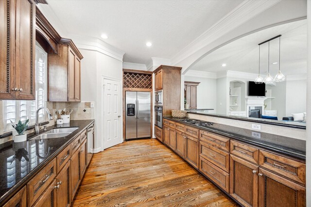 918 Detering St, Houston, TX 77007 - kitchen featuring stainless steel appliances, ornamental molding, brown cabinets, a fireplace, and dark stone counters
