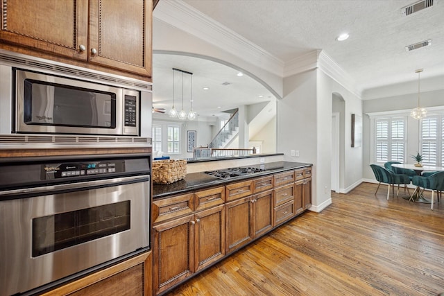 918 Detering St, Houston, TX 77007 - kitchen featuring stainless steel appliances, brown cabinets, arched walkways, ornamental molding, and light wood-type flooring