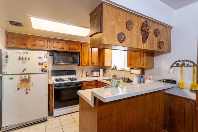 7726 Melanie St, Houston, TX 77016 - kitchen featuring freestanding refrigerator, black microwave, gas range, and brown cabinets