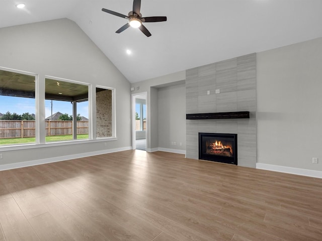 14328 Moonlit Creek Ct, Montgomery, TX 77316 - unfurnished living room featuring high vaulted ceiling, a tiled fireplace, a ceiling fan, and wood finished floors