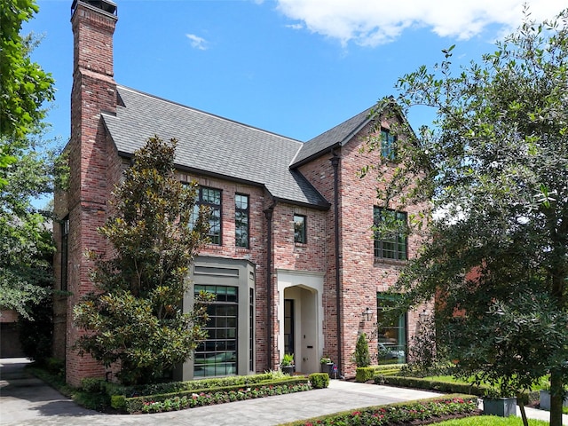 3028 Locke Ln, Houston, TX 77019 - tudor-style house with brick siding, a chimney, and roof with shingles