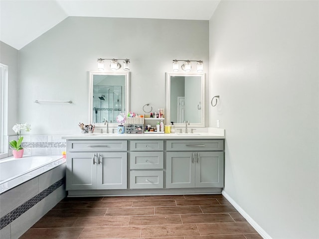 7902 Granite Ridge Ln, Houston, TX 77095 - bathroom with a shower stall, double vanity, lofted ceiling, a bath, and wood tiled floors