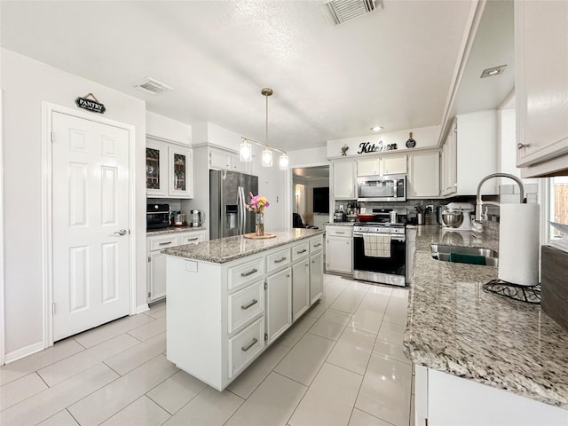 7902 Granite Ridge Ln, Houston, TX 77095 - kitchen with stainless steel appliances, a kitchen island, light stone counters, white cabinets, and tasteful backsplash