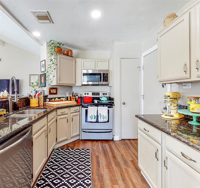 3114 Whetrock Ln, Sugar Land, TX 77479 - kitchen featuring appliances with stainless steel finishes, light wood-style flooring, dark stone countertops, recessed lighting, and a peninsula