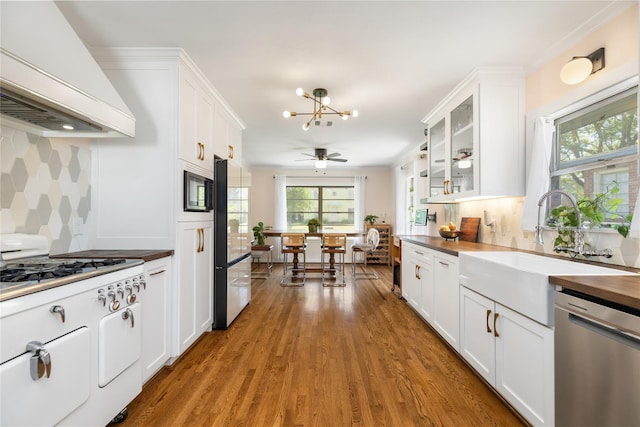 6625 Fairfield St, Houston, TX 77023 - kitchen featuring dishwasher, premium range hood, fridge, white cabinetry, and healthy amount of natural light