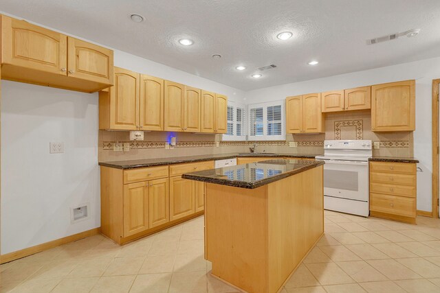 123 Sea Gull Dr, Livingston, TX 77351 - kitchen with white range with electric cooktop, a center island, light brown cabinets, dark stone countertops, and tasteful backsplash