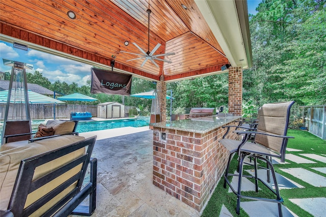 145 Bronze Bow Dr, Montgomery, TX 77316 - fenced backyard with a storage shed, an outdoor bar, a patio area, a ceiling fan, and exterior kitchen