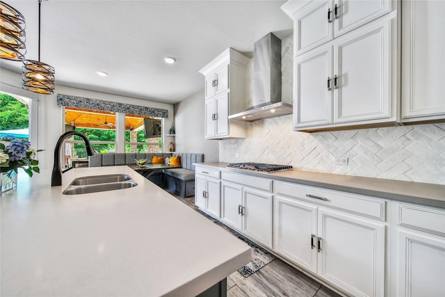 145 Bronze Bow Dr, Montgomery, TX 77316 - kitchen with wall chimney exhaust hood, stainless steel gas cooktop, tasteful backsplash, white cabinets, and hanging light fixtures