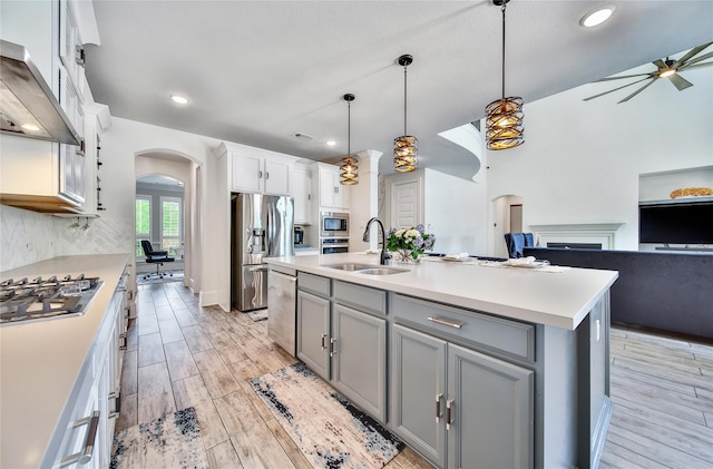 145 Bronze Bow Dr, Montgomery, TX 77316 - kitchen featuring arched walkways, wall chimney exhaust hood, appliances with stainless steel finishes, gray cabinets, and light countertops