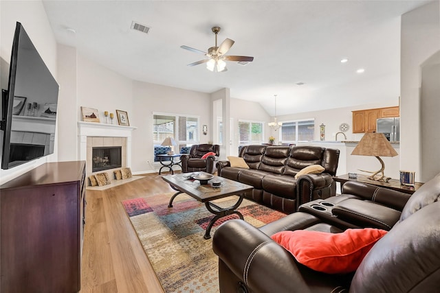 6318 Crystal Forest Trl, Katy, TX 77493 - living room featuring a ceiling fan, wood finished floors, a tile fireplace, vaulted ceiling, and a chandelier