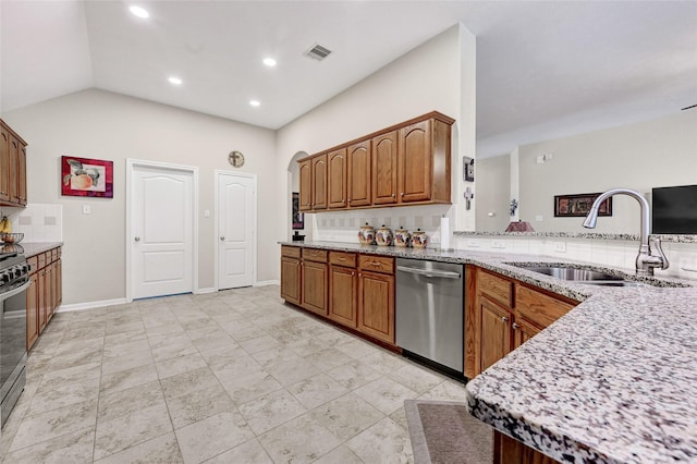 6318 Crystal Forest Trl, Katy, TX 77493 - kitchen featuring stainless steel appliances, backsplash, light stone counters, brown cabinetry, and recessed lighting
