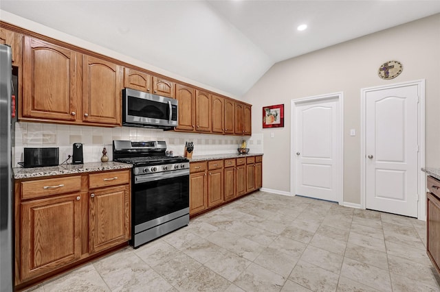 6318 Crystal Forest Trl, Katy, TX 77493 - kitchen featuring stainless steel appliances, lofted ceiling, decorative backsplash, brown cabinetry, and light stone counters