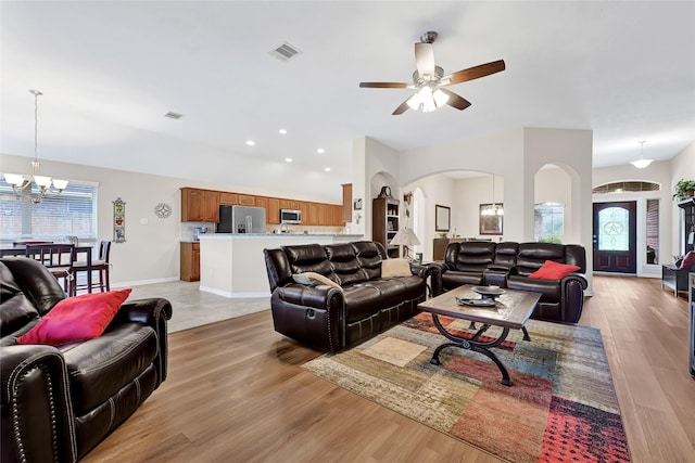 6318 Crystal Forest Trl, Katy, TX 77493 - living room with arched walkways, a ceiling fan, a chandelier, light wood finished floors, and recessed lighting