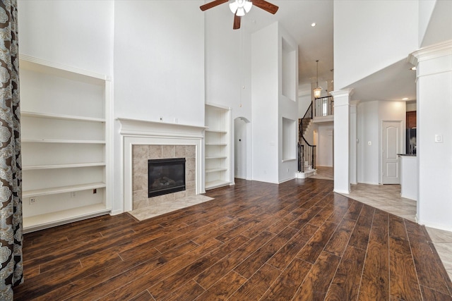 26314 Planters Heath, Katy, TX 77494 - unfurnished living room featuring a high ceiling, a ceiling fan, a tile fireplace, wood finished floors, and stairway