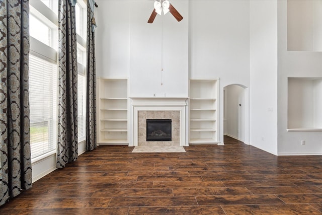 26314 Planters Heath, Katy, TX 77494 - unfurnished living room featuring a high ceiling, ceiling fan, wood finished floors, a tile fireplace, and arched walkways