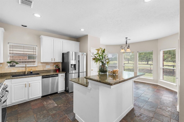 21519 San Marino Dr, Katy, TX 77450 - kitchen featuring stainless steel appliances, stone tile flooring, decorative backsplash, a textured ceiling, and white cabinetry