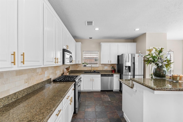 21519 San Marino Dr, Katy, TX 77450 - kitchen with stainless steel appliances, decorative backsplash, white cabinets, recessed lighting, and dark stone finish floors