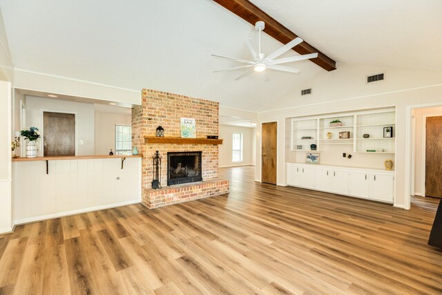 2910 Castle Ct, Pearland, TX 77581 - unfurnished living room with ceiling fan, plenty of natural light, a fireplace, beamed ceiling, and light wood finished floors