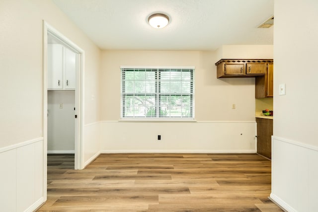 2910 Castle Ct, Pearland, TX 77581 - unfurnished dining area with light wood-style floors and wainscoting