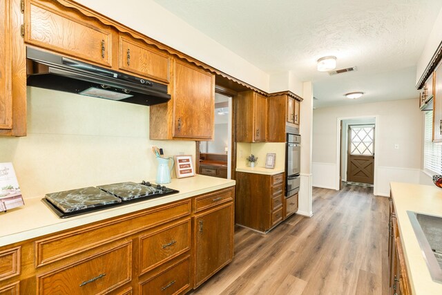 2910 Castle Ct, Pearland, TX 77581 - kitchen with under cabinet range hood, black electric stovetop, a warming drawer, light countertops, and stainless steel oven
