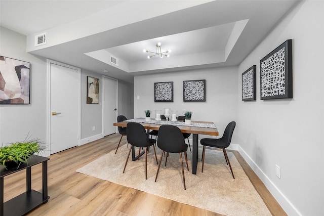 10370 Longmont Dr, Houston, TX 77042 - dining space featuring a tray ceiling, light wood finished floors, and a chandelier