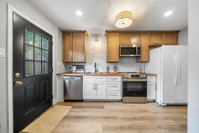 10370 Longmont Dr, Houston, TX 77042 - kitchen with appliances with stainless steel finishes, backsplash, light wood-style flooring, recessed lighting, and butcher block countertops