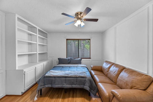 8023 Pine Falls Dr, Houston, TX 77095 - bedroom with light wood finished floors, a decorative wall, a textured ceiling, and a ceiling fan