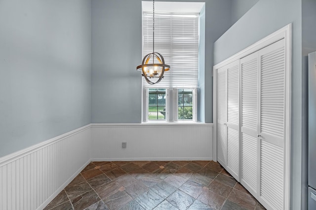 8023 Pine Falls Dr, Houston, TX 77095 - unfurnished dining area with wainscoting, a chandelier, and stone tile flooring