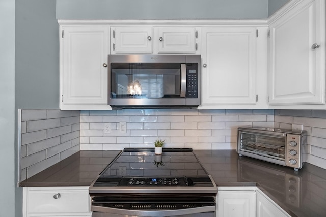 8023 Pine Falls Dr, Houston, TX 77095 - kitchen featuring stainless steel microwave, electric range, dark countertops, white cabinetry, and tasteful backsplash