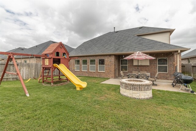 9418 Mcdowell Dr, Richmond, TX 77469 - back of property with a playground, roof with shingles, brick siding, a fenced backyard, and an outdoor fire pit