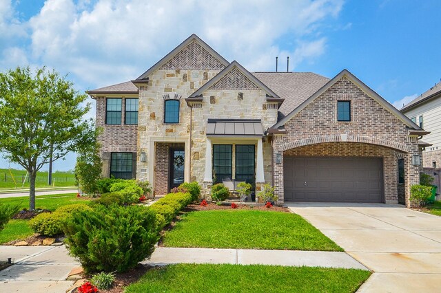 8703 Silver Crest Ln, Missouri City, TX 77459 - view of front of home featuring concrete driveway, a garage, a front lawn, stone siding, and brick siding