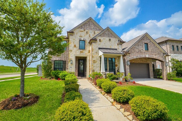 8703 Silver Crest Ln, Missouri City, TX 77459 - french country inspired facade with a front lawn, concrete driveway, stone siding, and a garage