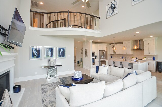 8703 Silver Crest Ln, Missouri City, TX 77459 - living room with ceiling fan, beverage cooler, a towering ceiling, recessed lighting, and a fireplace with raised hearth